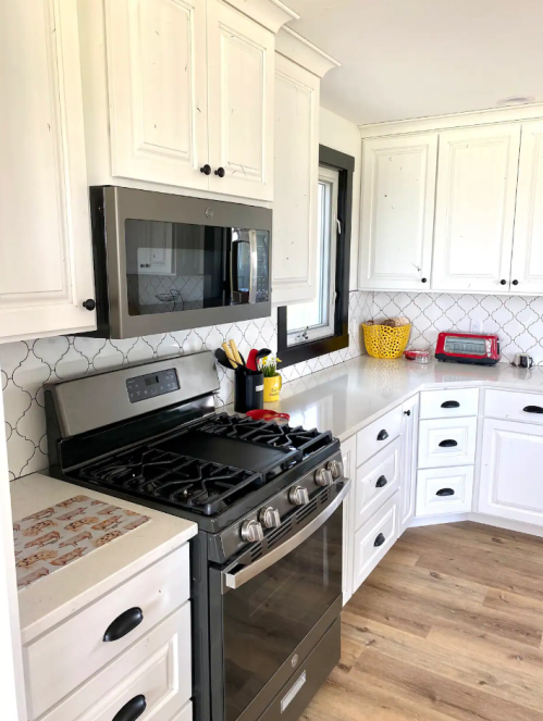 A modern kitchen featuring white cabinets, a stainless steel stove, microwave, and a colorful bowl on the counter.